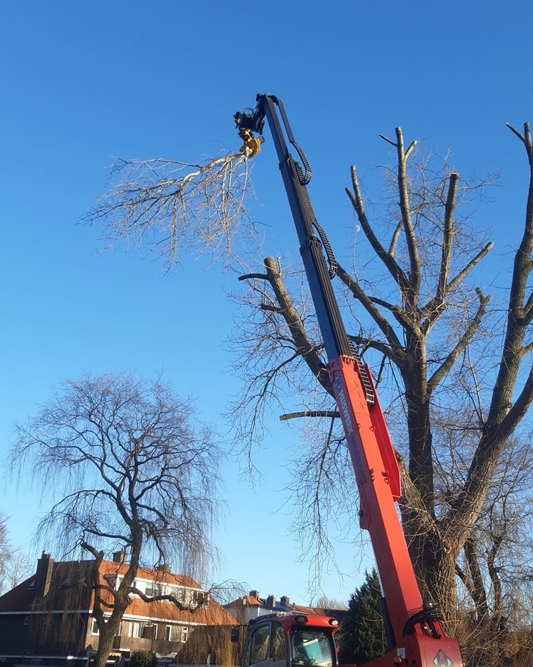 Rode telekraan met zaagklem tilt een kroondeel over de huizen, blauwe lucht